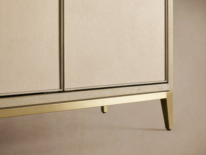 Close-up of Malone Cabinet door with beige shagreen-embossed leather, gold handle, and light wood interior shelves.