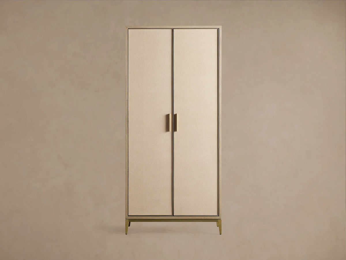 Close-up of Malone Cabinet: two light beige doors with textured shagreen insets, light wood frame, and sleek gold metallic legs.