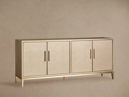 Malone Sideboard in a light shade, featuring four shagreen-textured doors with gold vertical handles, on a matching metallic base.