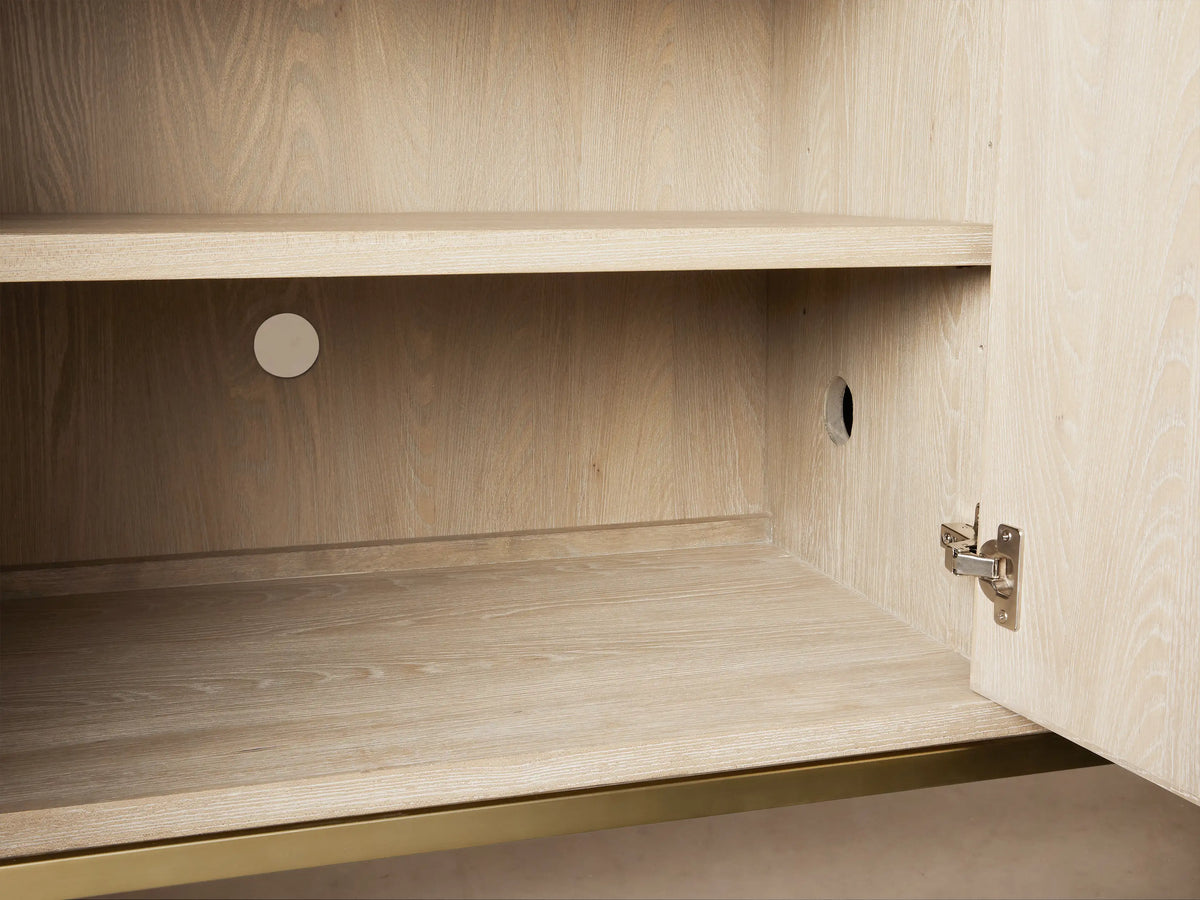 Close-up of Malone Sideboard with light wood top, two pale beige shagreen-textured doors, and metallic gold pulls.