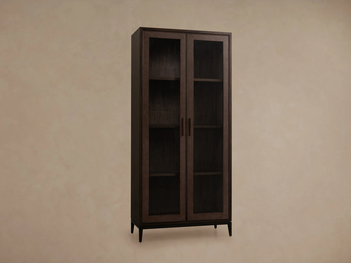 Malone Glass Cabinet corner with dark walnut finish, visible wooden shelf, textured reconstituted leather inset, and sleek metallic handle.