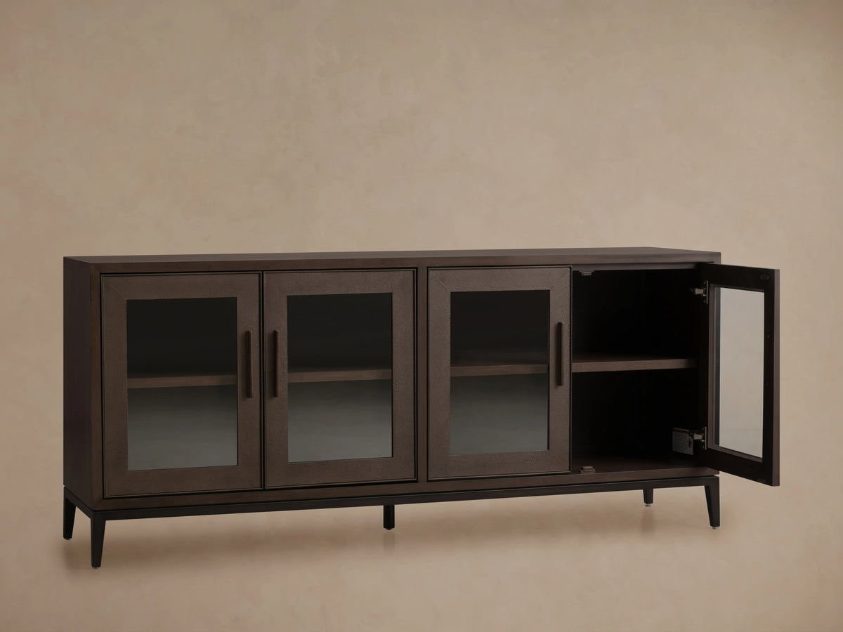 Malone Sideboard in dark walnut, featuring four glass doors, sleek handles, and visible interior shelves, on a wood floor.