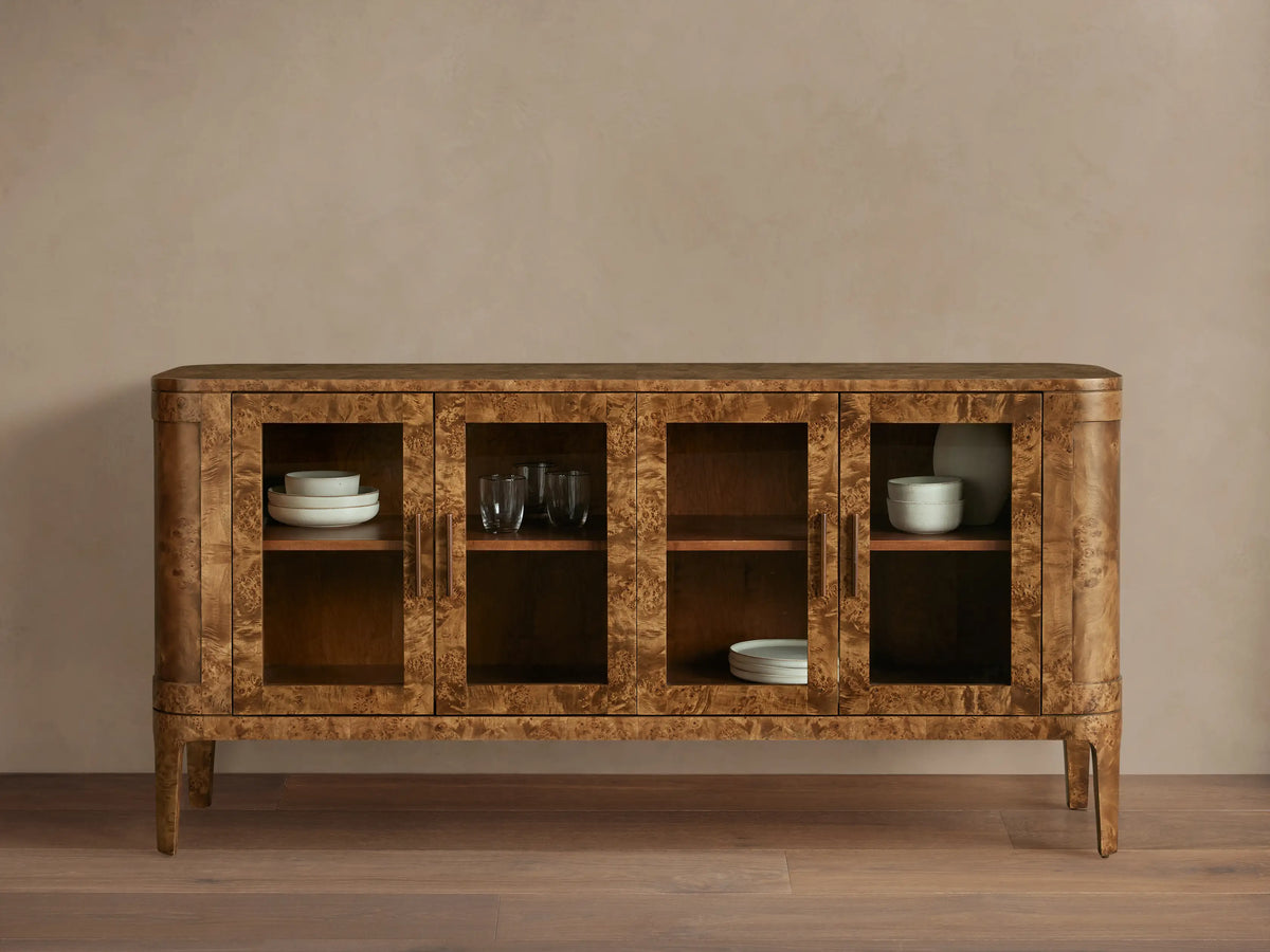 Front view of the mappa burl wood Mogadore Sideboard. Four glass doors, brass handles. Shelves display white bowls and glasses.