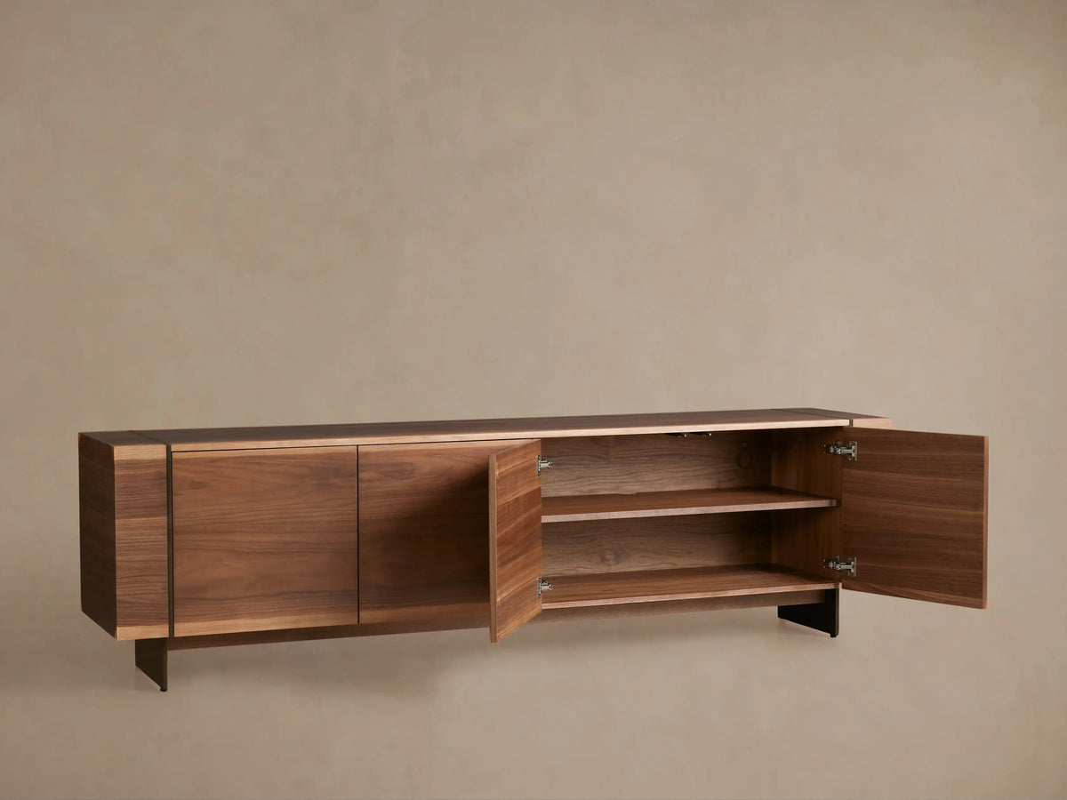 Long Mihaela Media Console in dark walnut veneer with four doors, oil-rubbed bronze accents, light wood trim, and metal legs.