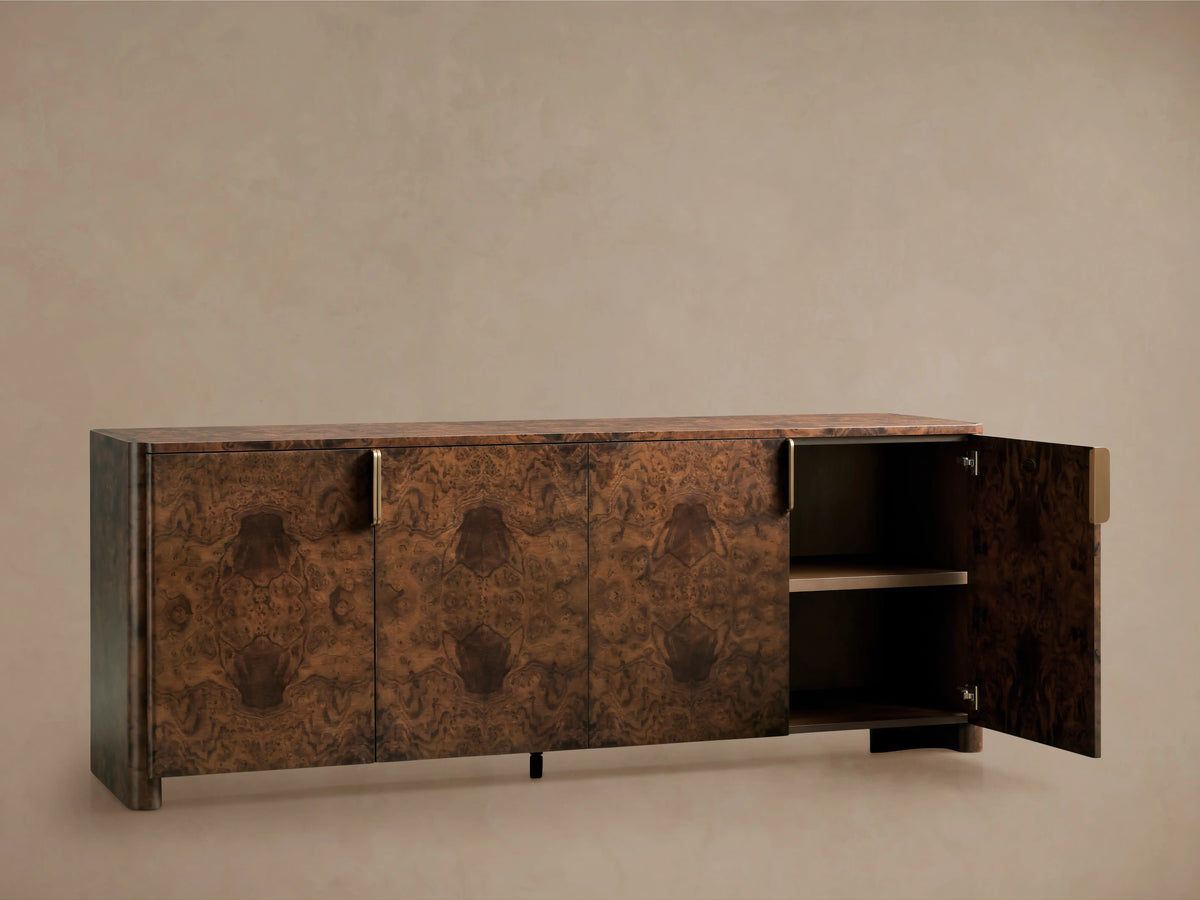 Morley Sideboard crafted from walnut burl wood with auburn finish, features swirling patterns, four doors, one open showing shelves, and antique brass-finished pulls.