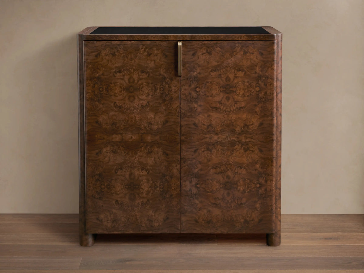 Morley Bar Cabinet with a rich dark brown wood finish, intricate grain pattern, sleek black top, and single vertical handle.
