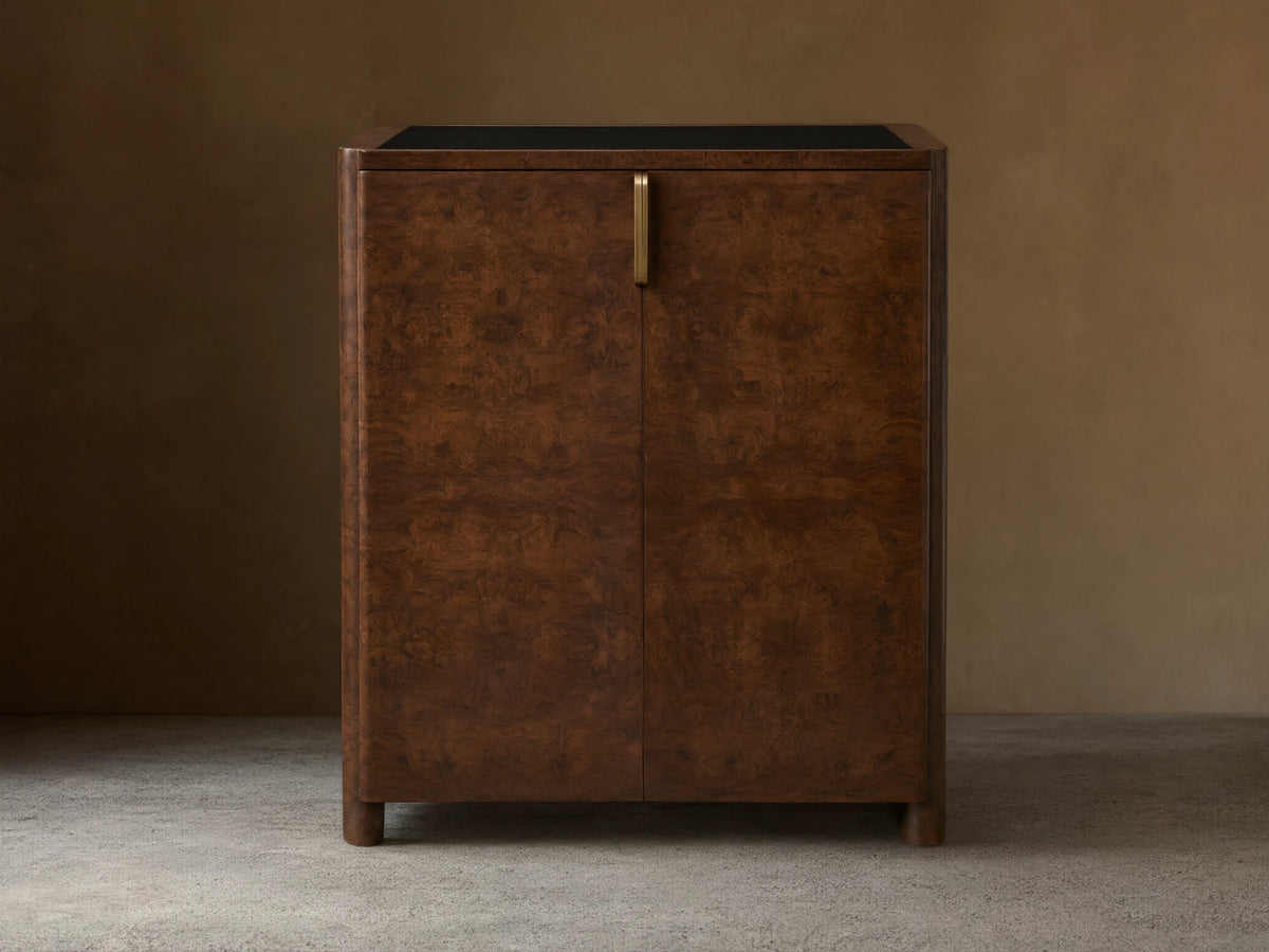 Morley Bar Cabinet with a rich dark brown wood finish, intricate grain pattern, sleek black top, and single vertical handle.