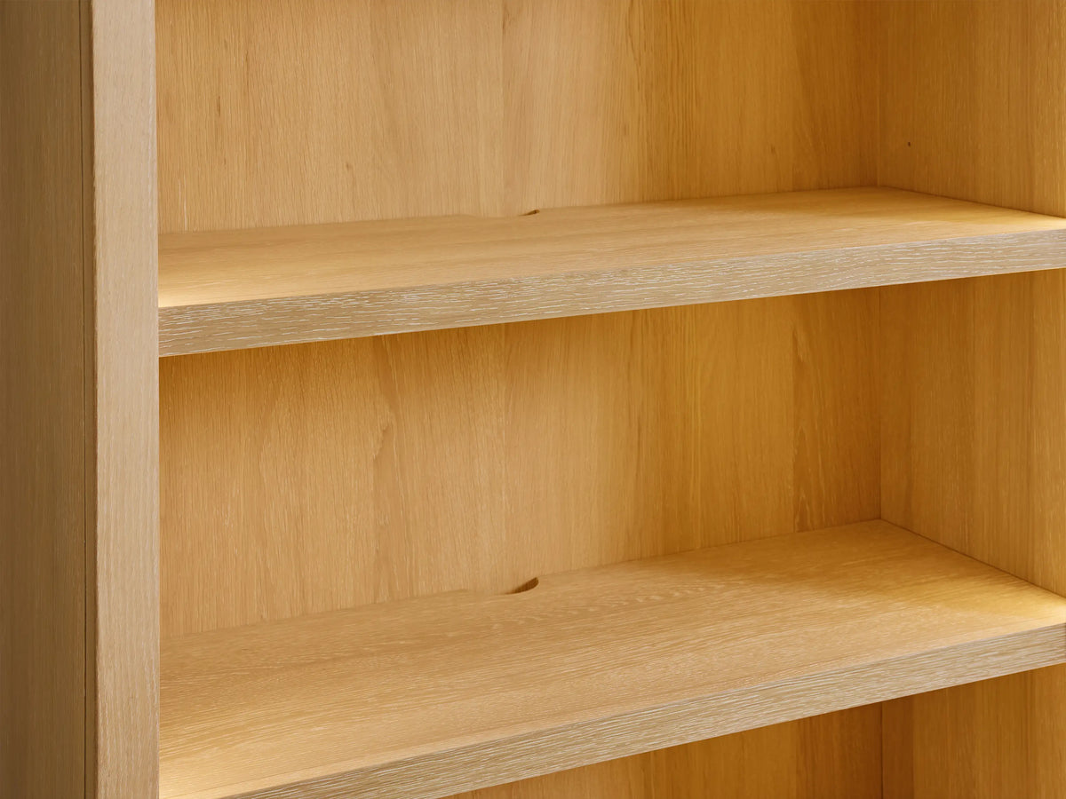 Close-up of Nason Modular Hutch Cabinet's light oak shelves in Sand finish, showing wood grain and a cord management hole.