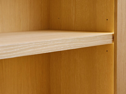 Close-up of a Nason Modular Hutch Cabinet with a light sand-finished white oak shelf, showing visible wood grain and adjustment holes.