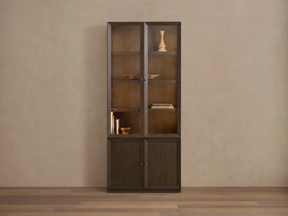 Nason Modular Glass Cabinet in dark Mocha finish. Tall unit with glass display tops, solid doors below, shelves, and decor items.