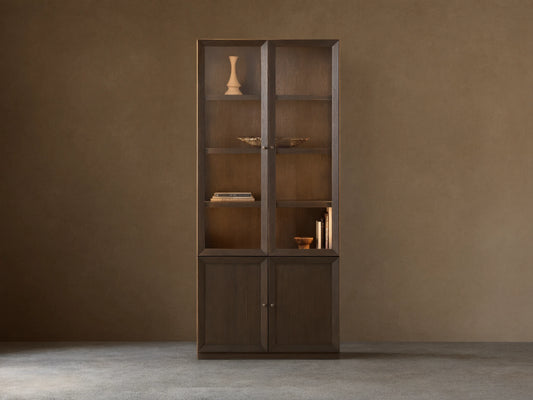 Nason Modular Glass Cabinet in dark Mocha finish. Tall unit with glass display tops, solid doors below, shelves, and decor items.