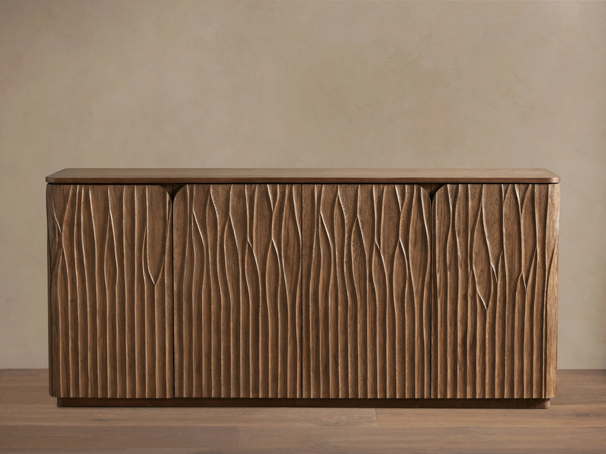 Norris Sideboard: Medium brown wooden sideboard with a flat top and four doors displaying a distinct wavy carved vertical pattern.