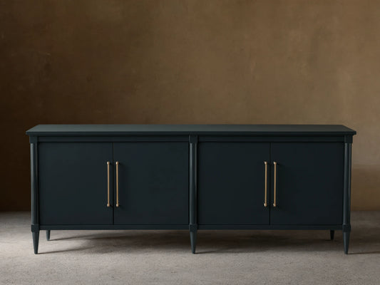 Oakleigh Sideboard in dark finish with brass hardware, four doors, on a wooden floor against a beige wall.