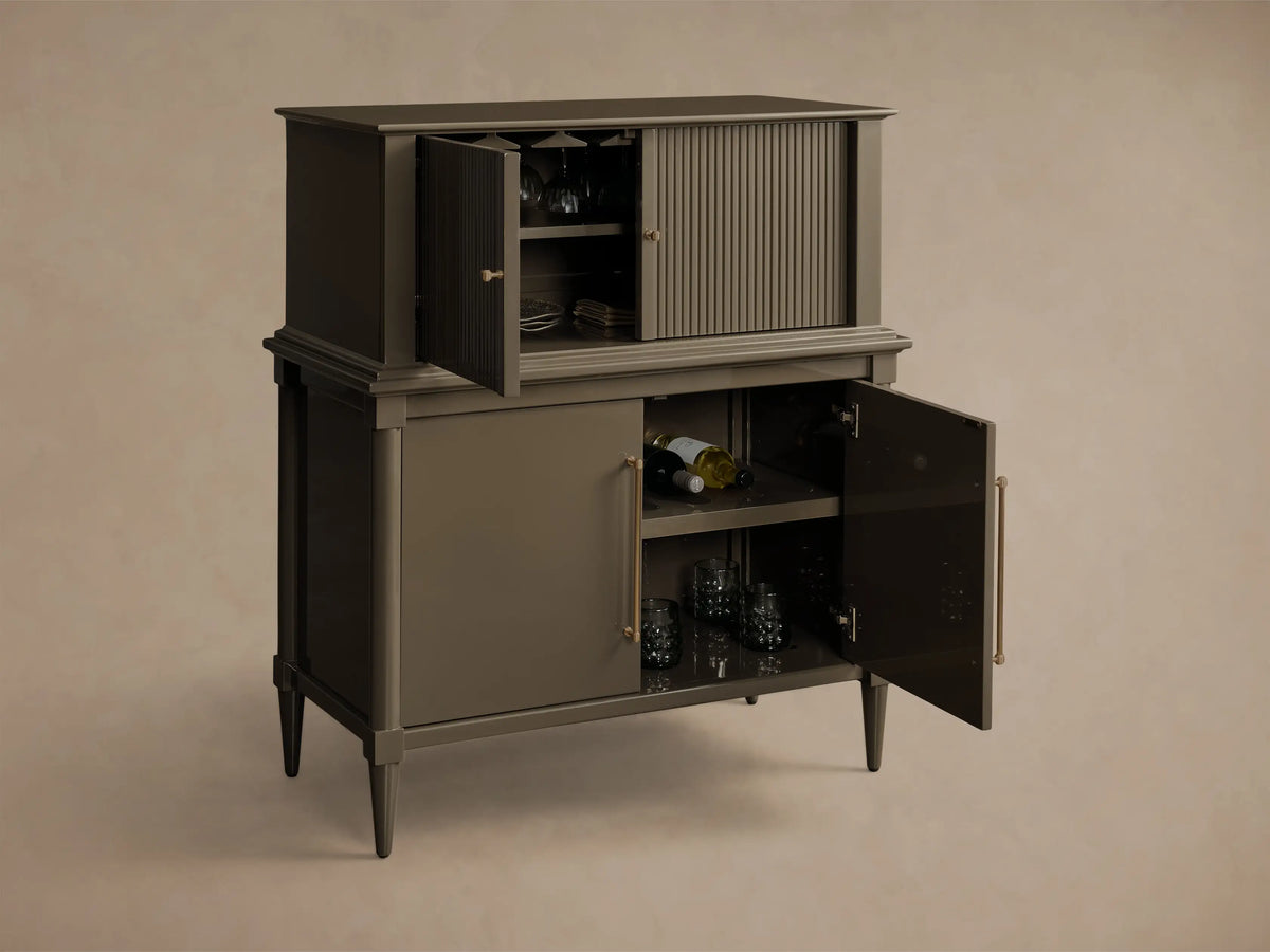 Front view of deep taupe Oakleigh Bar Cabinet with open reeded upper door showing stemware, and open lower door revealing wine and glasses.
