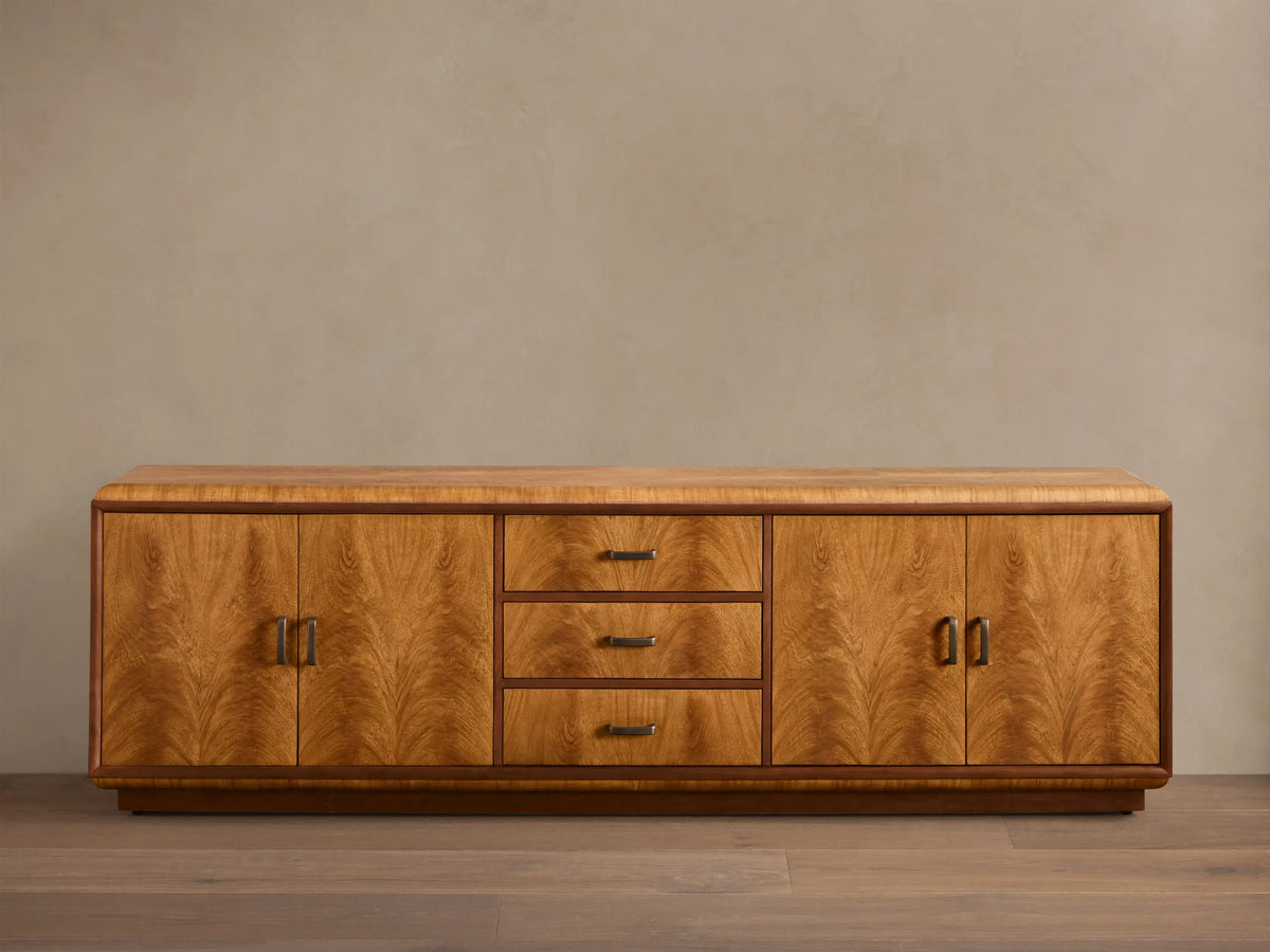 Front view of the Palma Media Console, showing light brown cerajeira wood veneer with cathedral graining, dark trim, and aged bronze hardware.