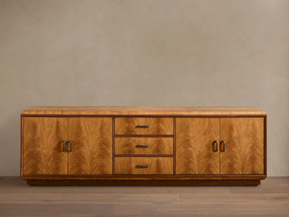 Front view of the Palma Media Console, showing light brown cerajeira wood veneer with cathedral graining, dark trim, and aged bronze hardware.