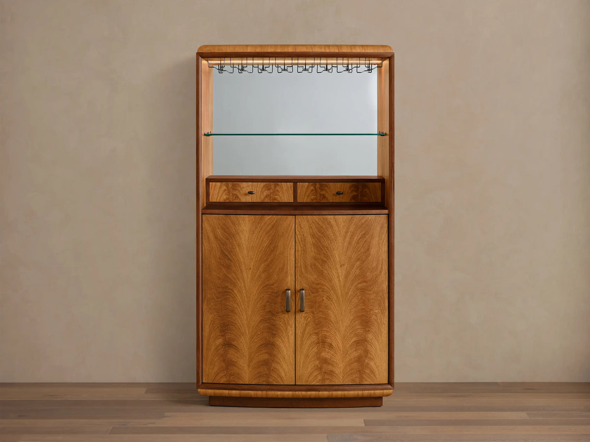 Front view of the Palma Bar, a wood bar cabinet with prominent cerajeira veneer graining, mirrored back, glass shelf, and LED lighting.