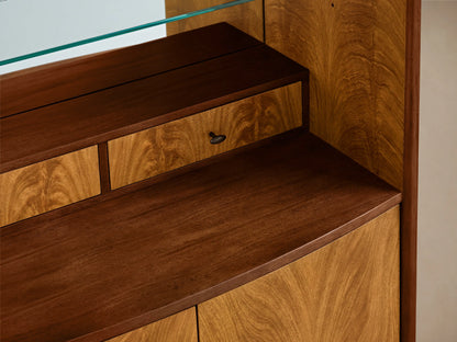 Front view of Palma Bar, wood cabinet with dramatic cerajeira veneer grain, aged bronze hardware, mirrored back, glass shelf, stemware rack.