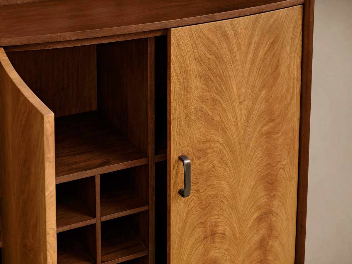 Close-up of Palma Bar, featuring rich brown cerajeira and primavera wood veneers with dramatic cathedral graining and a glass shelf.