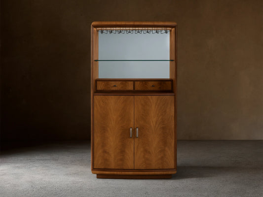 Front view of the Palma Bar, a wood bar cabinet with prominent cerajeira veneer graining, mirrored back, glass shelf, and LED lighting.