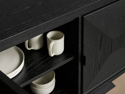 Close-up of open ebony Pelham Sideboard, showcasing visible wood grain, interior shelves with light ceramic mugs, plates, and bowls.