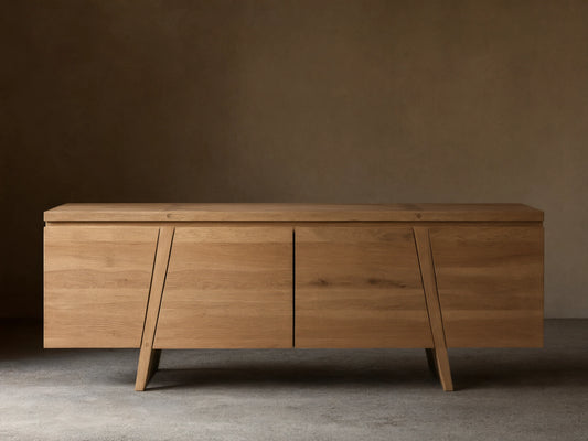 Panta Sideboard in light wood finish with four doors, angled side legs, and a flat top, set against a neutral wall.
