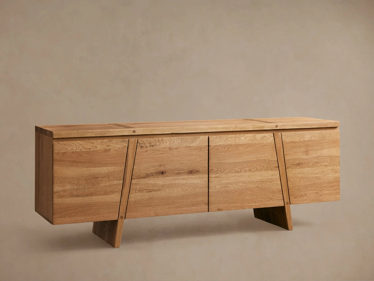 Panta Sideboard in light wood finish with four doors, angled side legs, and a flat top, set against a neutral wall.