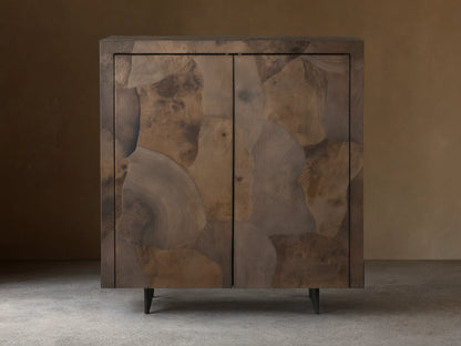 Polanco Bar Cabinet made from oyster-cut ash, showcasing varied textures and tones, with a steel base, set against a wooden floor.
