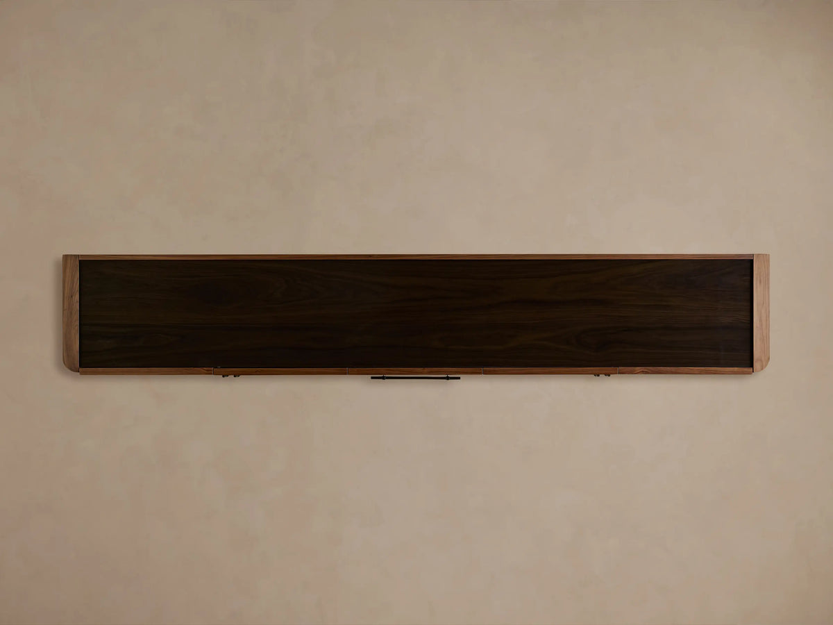 Piermont Sideboard in warm walnut with a smoked glass top, one cabinet door open revealing an interior shelf with books and decor.