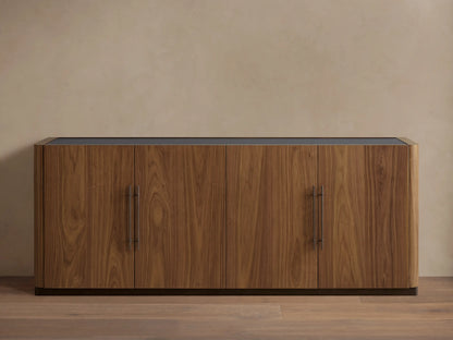 Piermont Sideboard: long walnut wood cabinet with smoked glass top, four doors, bronze handles, and dark bronze plinth base.