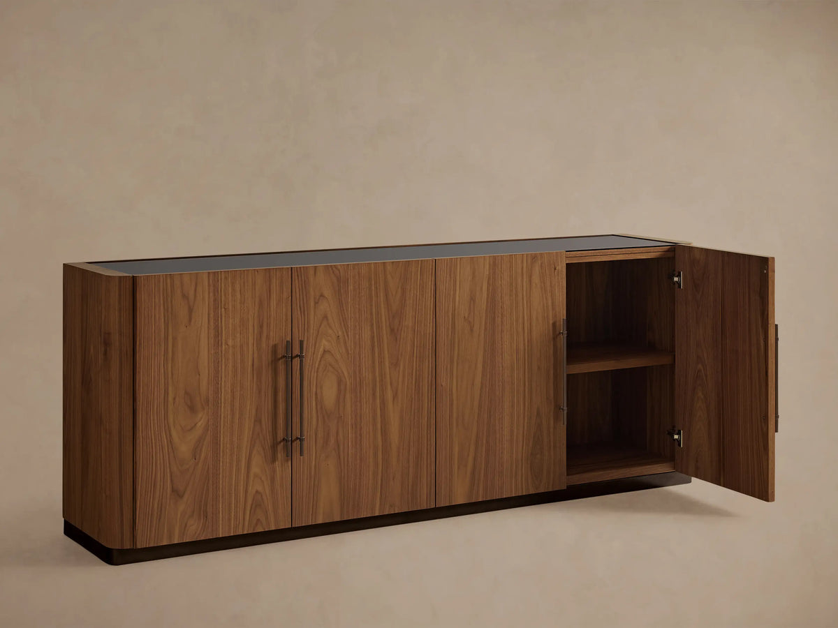 Piermont Sideboard: long walnut wood cabinet with smoked glass top, four doors, bronze handles, and dark bronze plinth base.