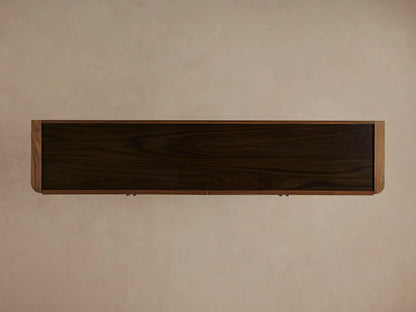 Piermont Sideboard: dark walnut cabinet, one door open revealing internal shelves with vase & book. Smoked glass top, bronze base.