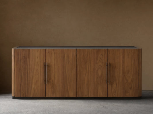 Piermont Sideboard: long walnut wood cabinet with smoked glass top, four doors, bronze handles, and dark bronze plinth base.