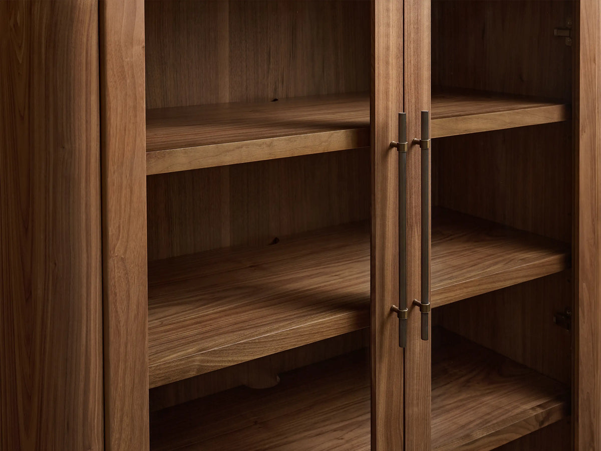 Piermont Modular Glass Cabinet. Tall dark walnut wood cabinet with rounded top. Upper glass doors, lower solid doors, bronze handles, plinth base.