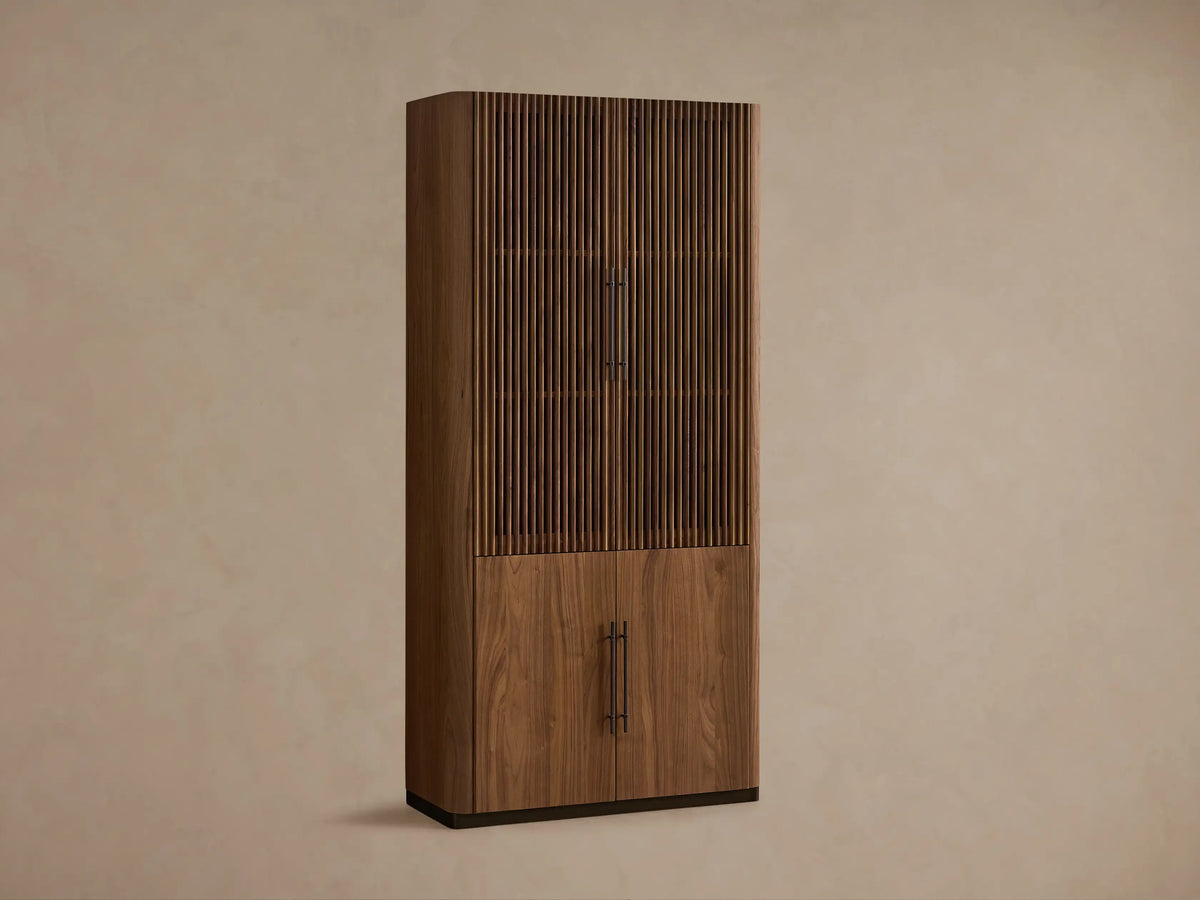 Angled view of dark walnut Piermont Modular Reeded Cabinet with reeded doors and bronze plinth base in a living room.