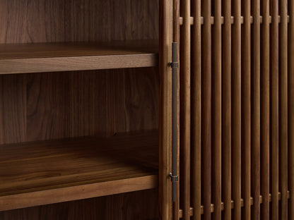 Close-up of Piermont Modular Reeded Cabinet. Dark walnut with reeded top, door open revealing shelves, bronze handle.