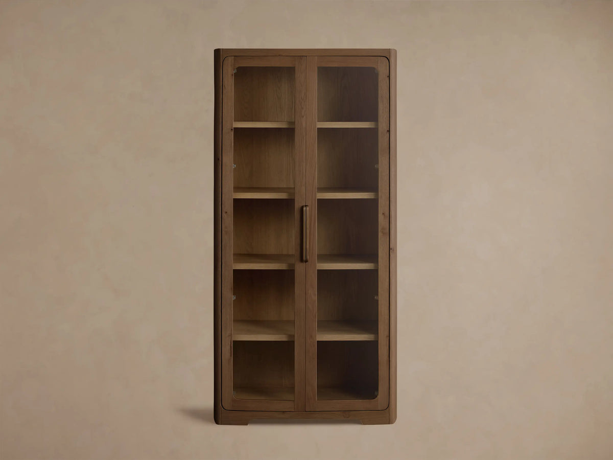 Front view of the brown oak finish Redding Glass Cabinet with two glass doors, four shelves, and an antique brass handle.