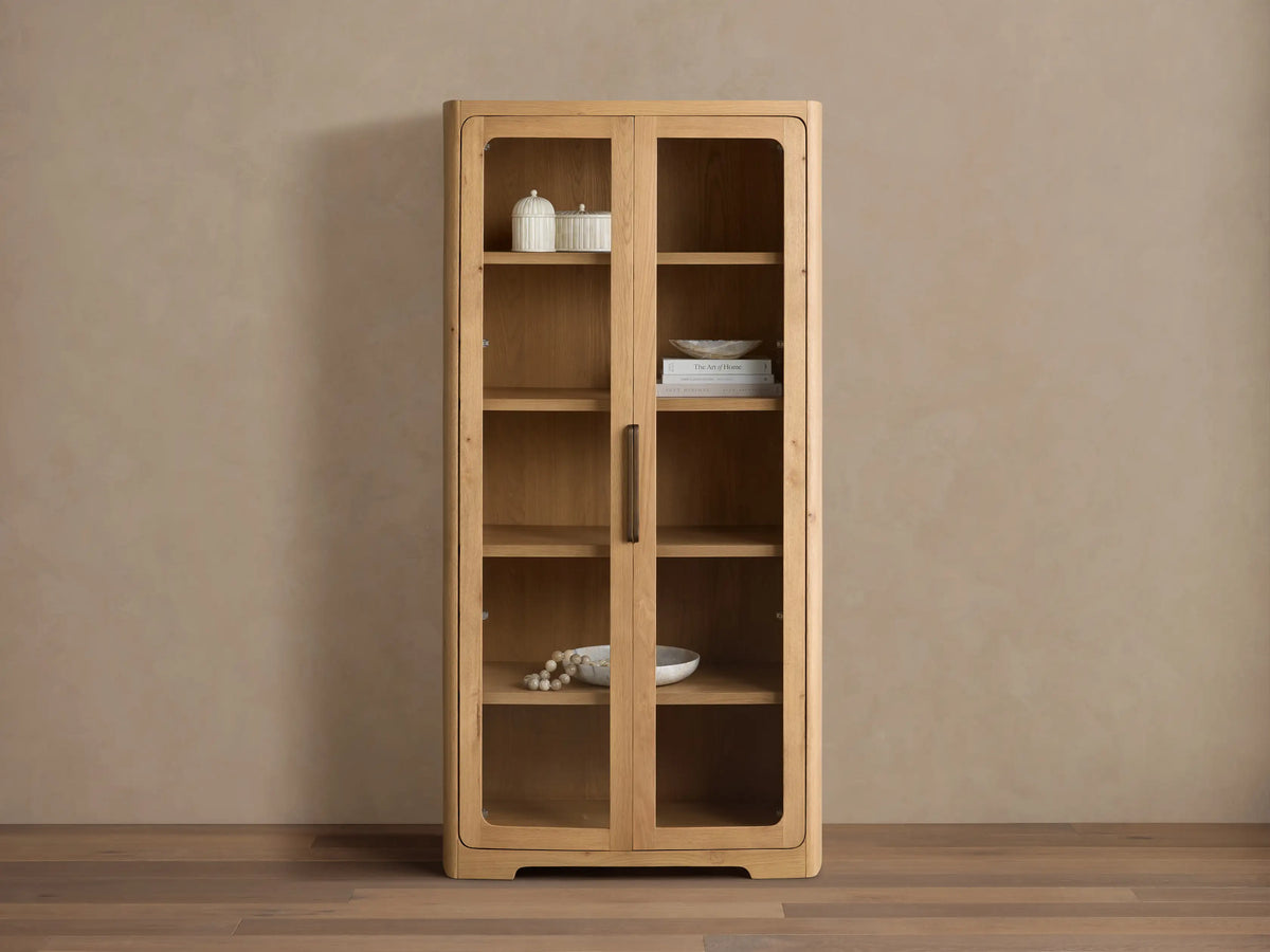 Front view of natural wood Redding Glass Cabinet with two glass doors, four shelves, and antique brass hardware.