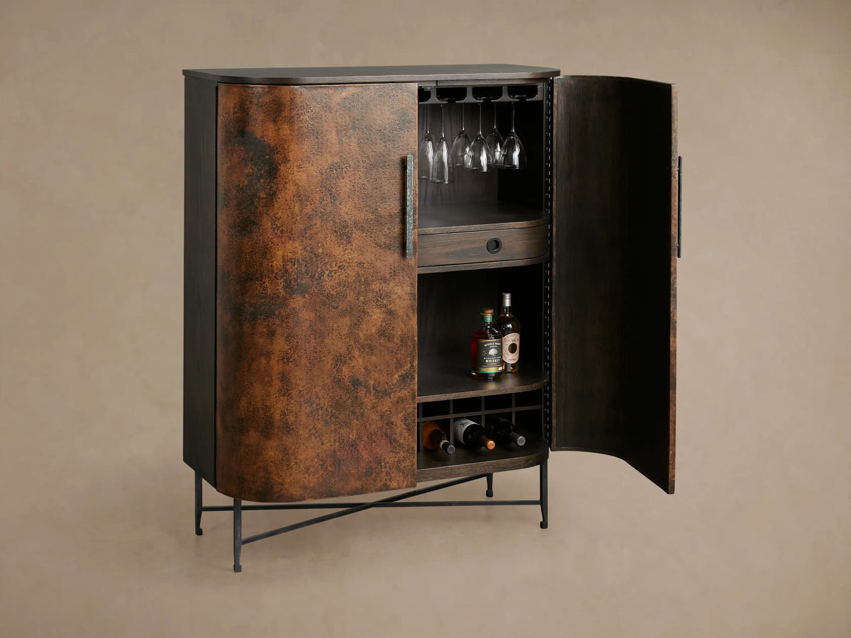 Ruiz Bar Cabinet: Curved, two-door cabinet with fiery orange-brown hand-hammered copper doors, black handles, dark top, and iron base.