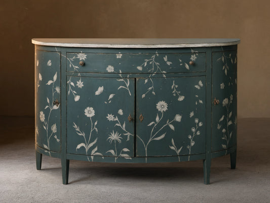 Front view of the distressed dark teal Sofia Bell'Arte Demilune Cabinet with white hand-painted floral and butterfly motifs and light top.