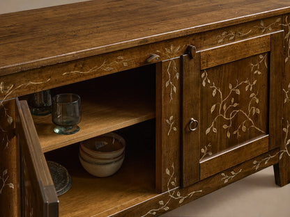 Front view of the brown Stefania Four-Door Buffet with one door open revealing shelves. Features hand-painted leaf decor and ring pull.