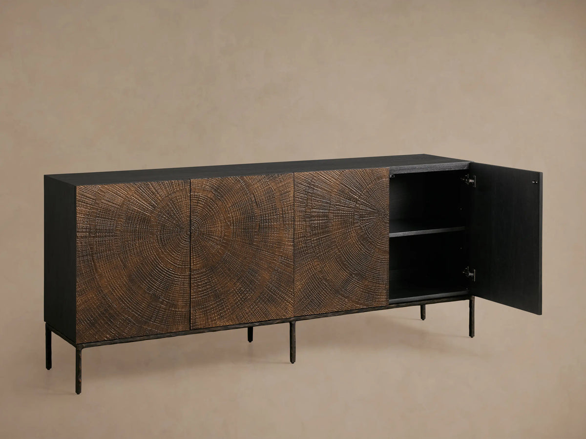 Theota Sideboard: dark brown teak wood with hand-stamped sunburst pattern across its 4 doors, black top, dark hammered aluminum legs.