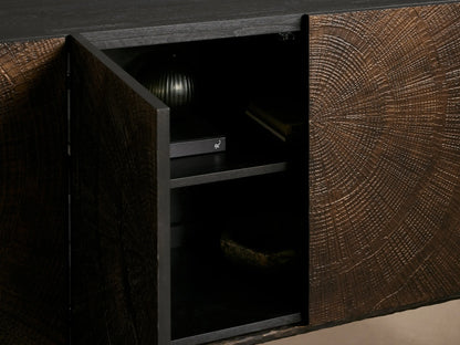 Close-up of Theota Sideboard's dark wood top with visible grain, meeting a textured brown door with a hand-stamped sunburst pattern.