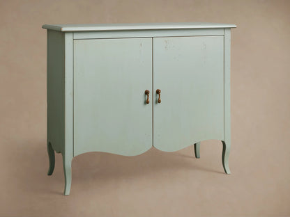 Varzi Cabinet in muted teal with curved legs and antique pendant pulls, against a neutral wall, on a wooden floor.