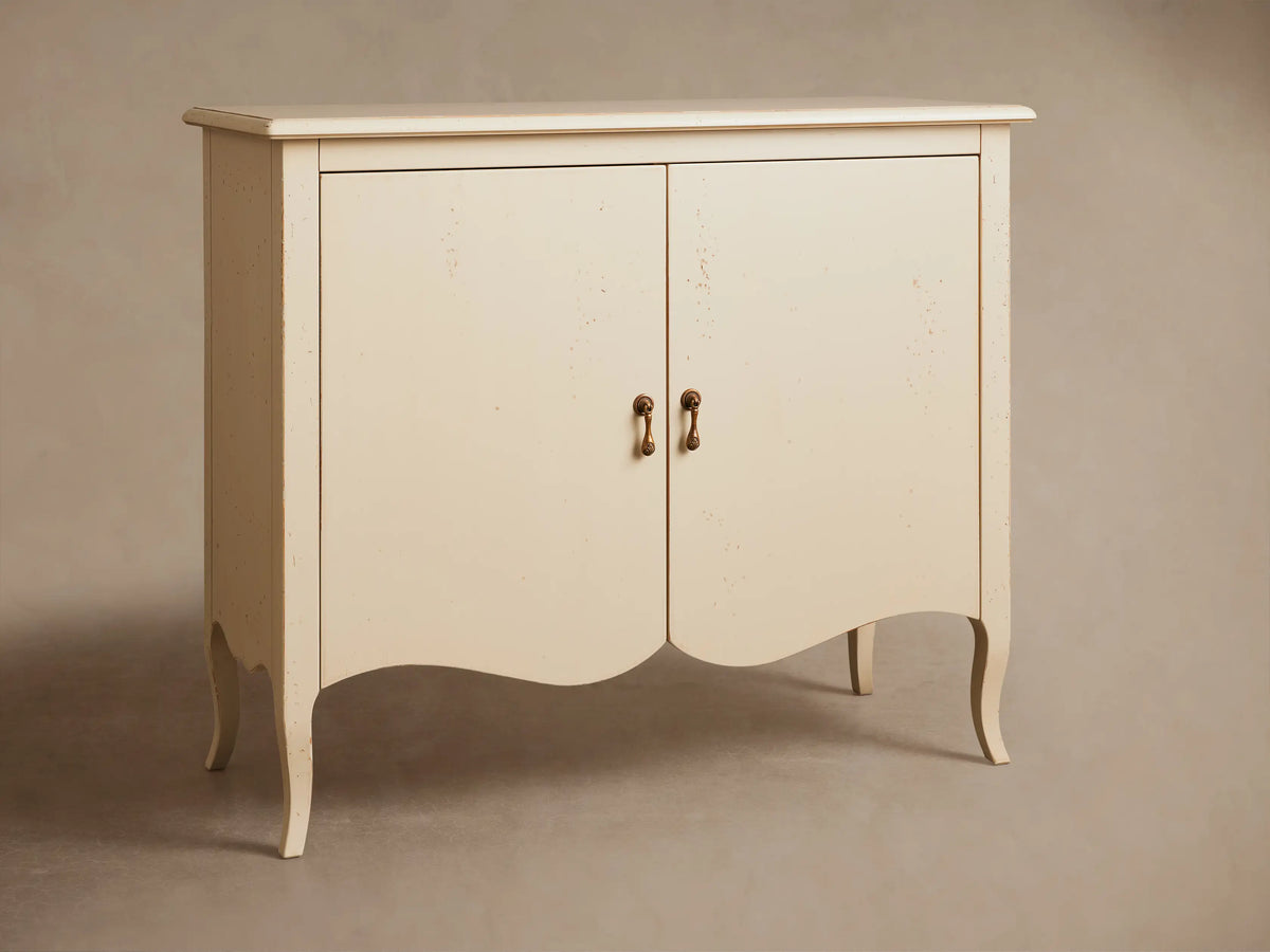 Varzi Cabinet in light cream with two doors and antique pendant pulls, standing on curved legs against a neutral wall.