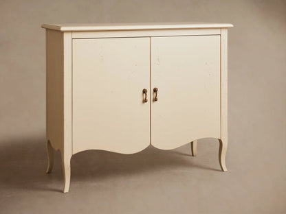 Varzi Cabinet in light cream with two doors and antique pendant pulls, standing on curved legs against a neutral wall.