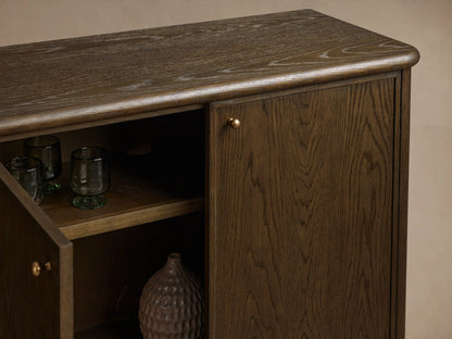 Warby Sideboard in rich mocha-toned oak wood, featuring four cabinet doors with brass pulls, two open revealing shelves inside.