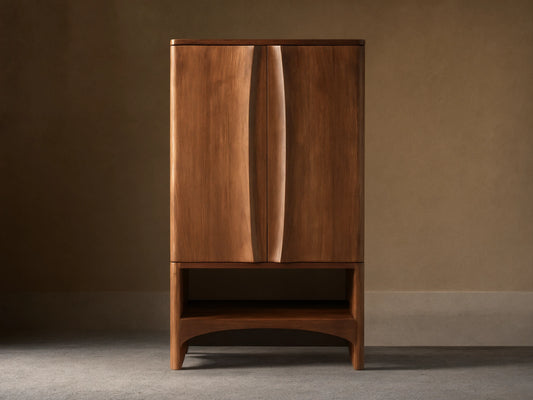 Westyn Bar Cabinet, medium brown wood, two doors with curved vertical finger pulls, and an open lower shelf.