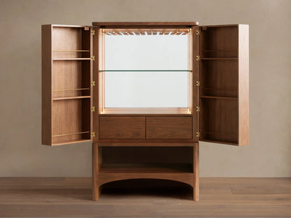 Westyn Bar Cabinet, medium brown wood, two doors with curved vertical finger pulls, and an open lower shelf.