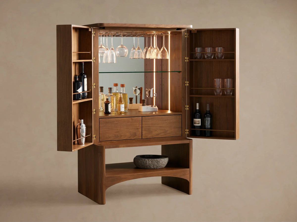 Close-up of Westyn Bar Cabinet interior showing brass stemware racks holding clear wine glasses, with a warm vertical LED light.